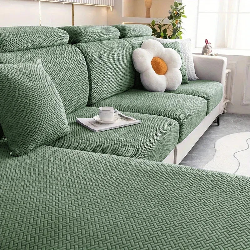 Green sectional sofa with a decorative pillow in a living room setting
