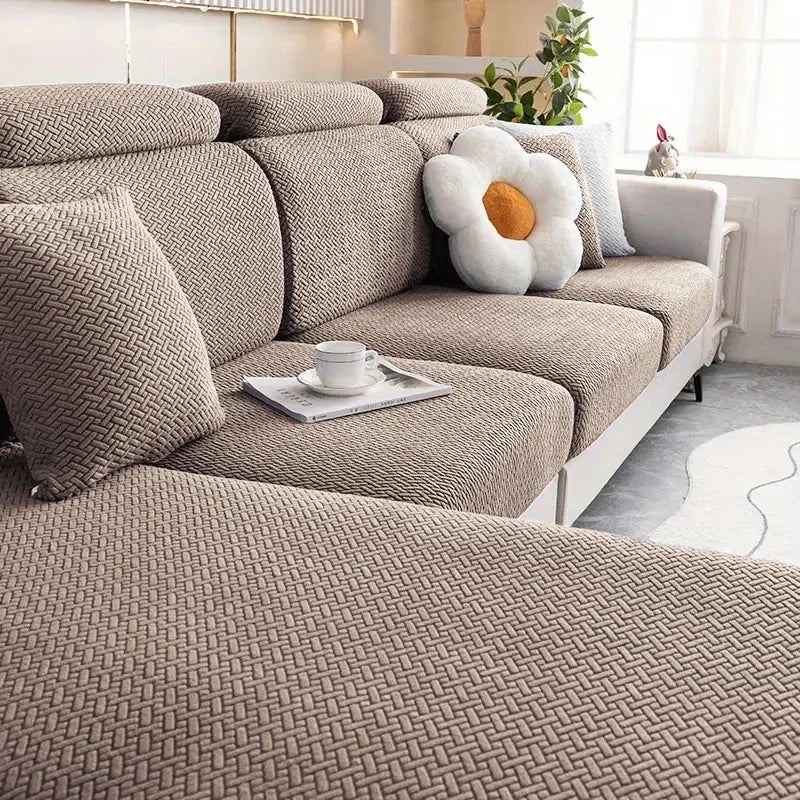 Beige sectional sofa with decorative pillows and a small table in a living room setting.