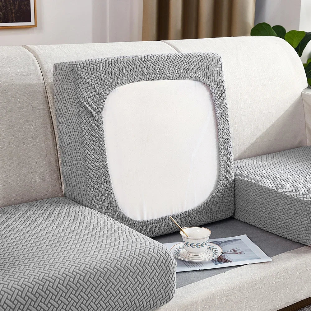 Gray textured pillow on a white sofa with a cup and plate on a magazine