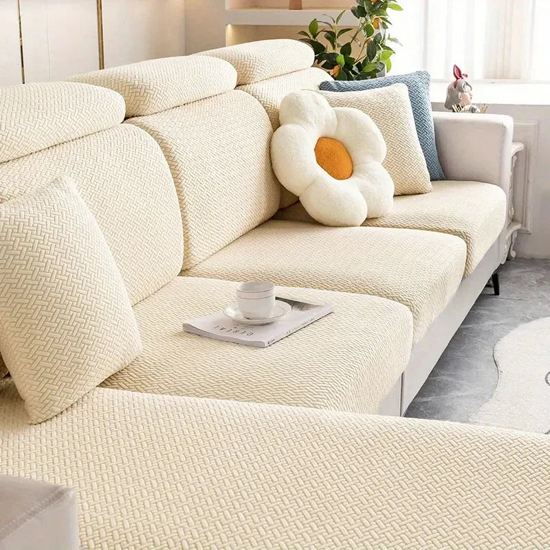 Beige sectional sofa with decorative pillows and a cup on a small table in a living room.